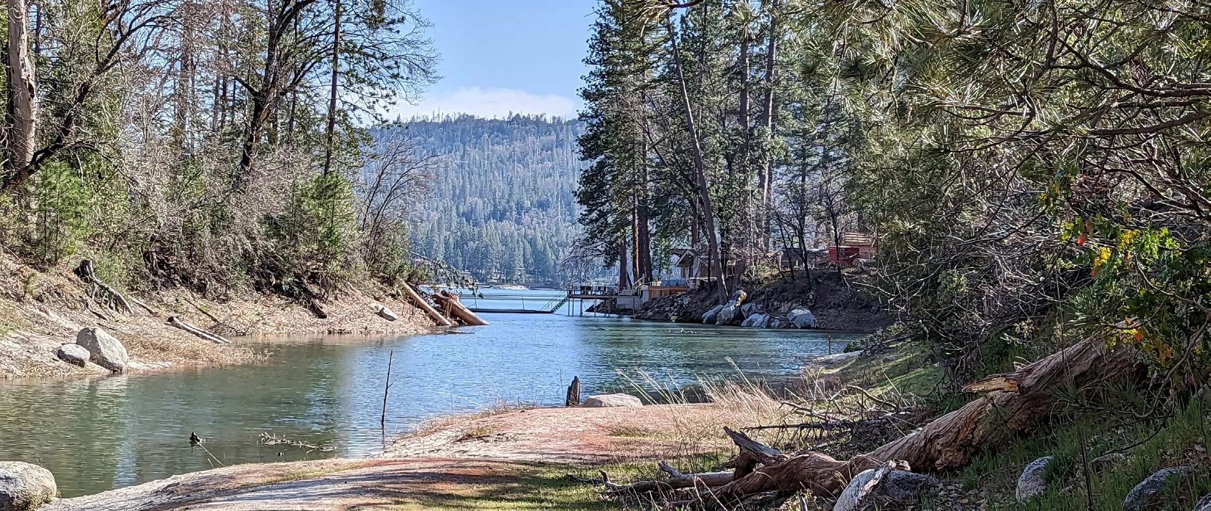 A cove of Bass Lake framed by pines and granite boulders, seen from the trail along the shore