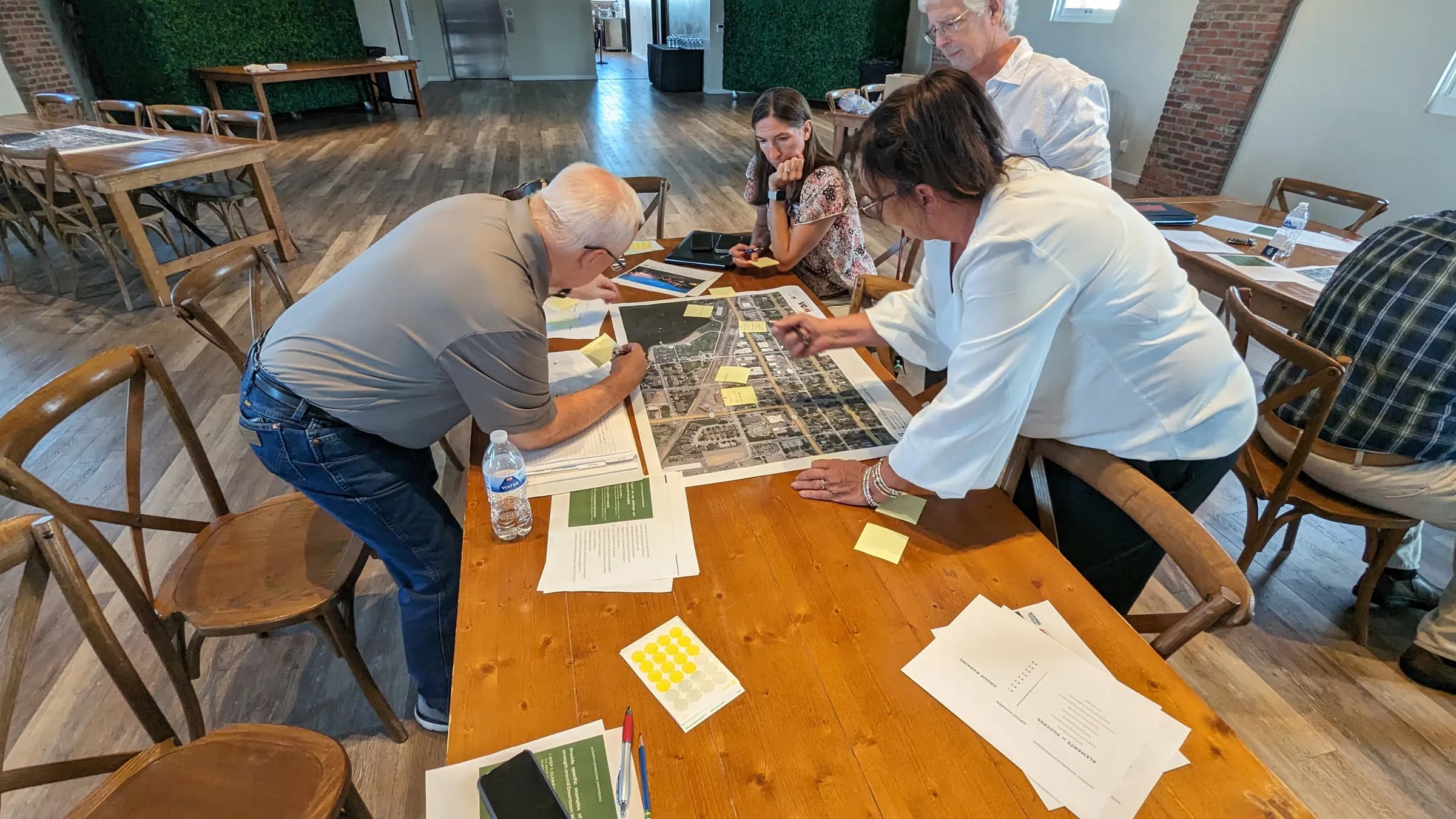 People marking up an aerial map of downtown Windsor at a planning workshop, with sticky notes and dot stickers around it